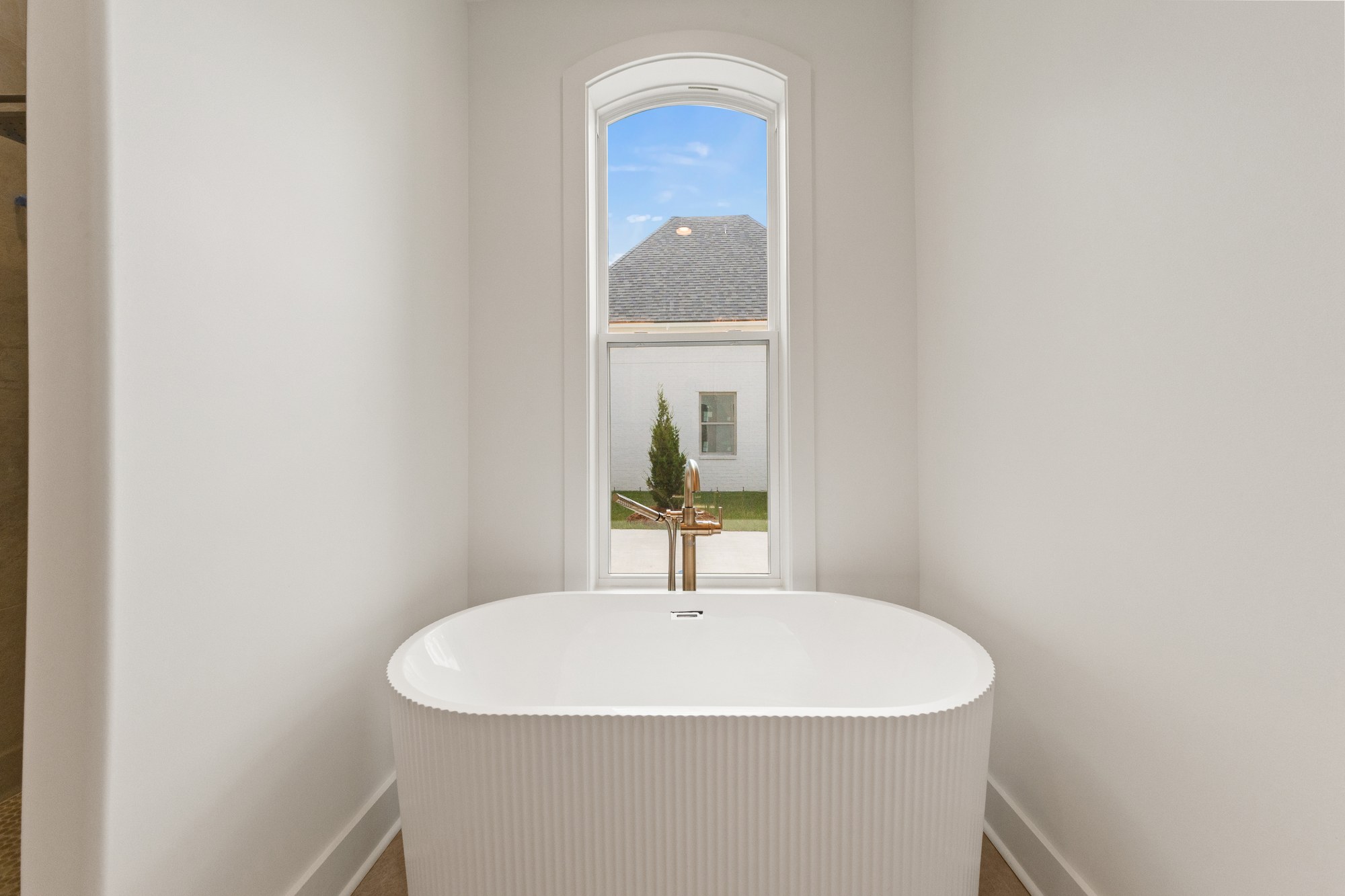 Freestanding tub beneath an arched window at 221 Gunter Grass